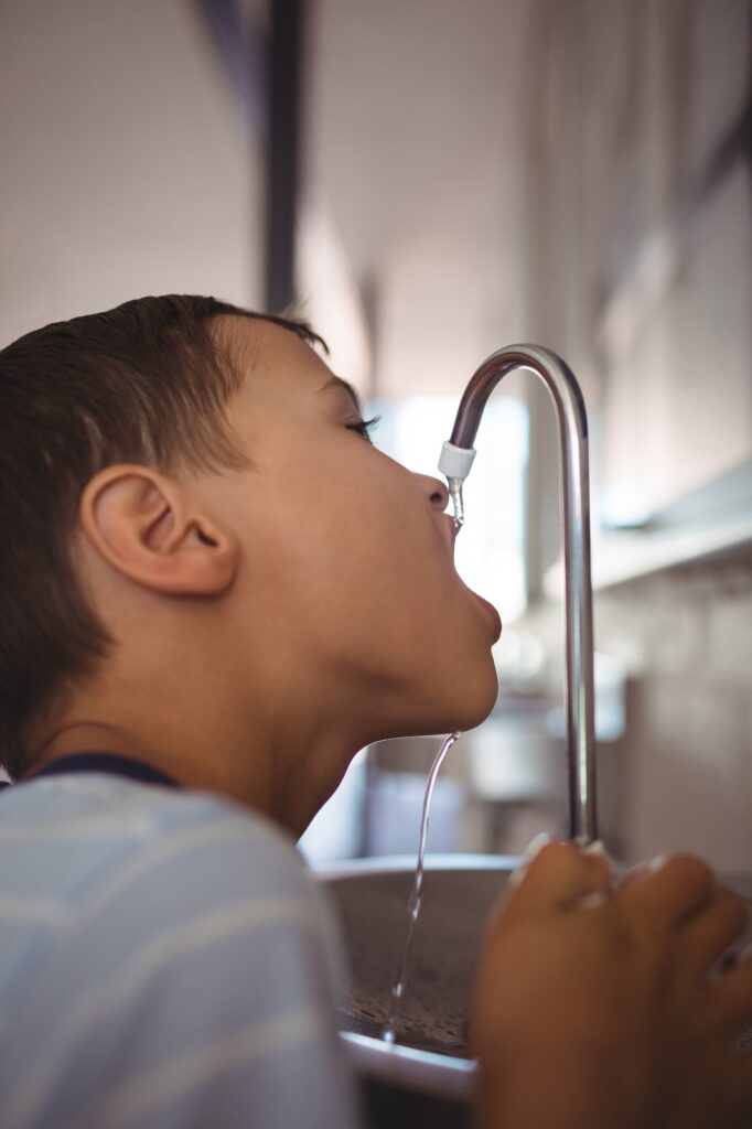 Close up of boy drinking water from faucet