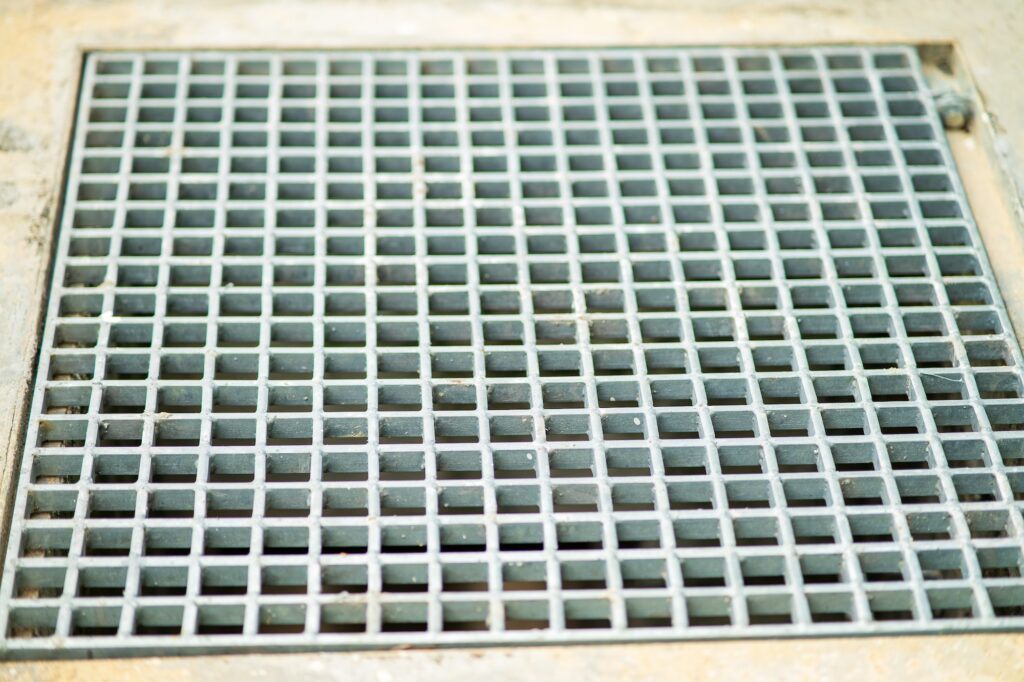 Closeup drain sump and grating on the floor outdoor.