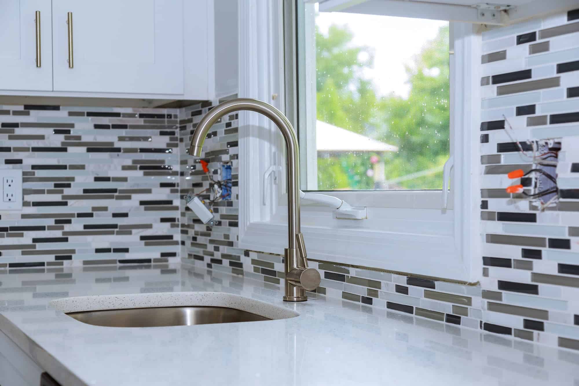 Faucet and kitchen faucet and countertop detail sink with brick wall
